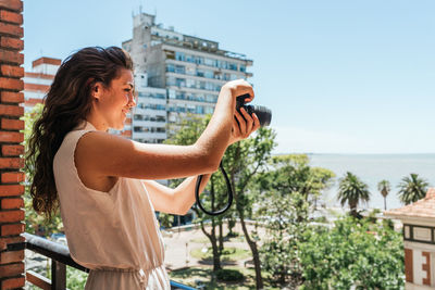 Midsection of woman photographing against sky