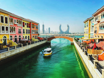 Bridge over canal amidst buildings in city against sky