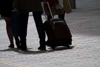 Business traveller walks through city with wheeled luggage