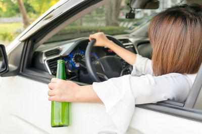 Woman with bottle sitting in car