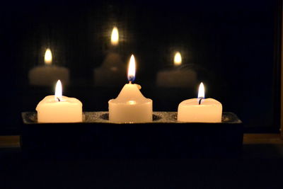 Close-up of illuminated tea light candles in darkroom