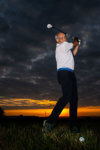 Man playing golf on field during sunset