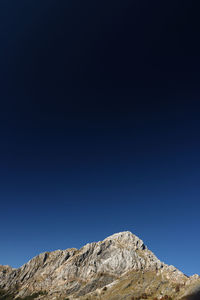 Low angle view of rocks against clear blue sky