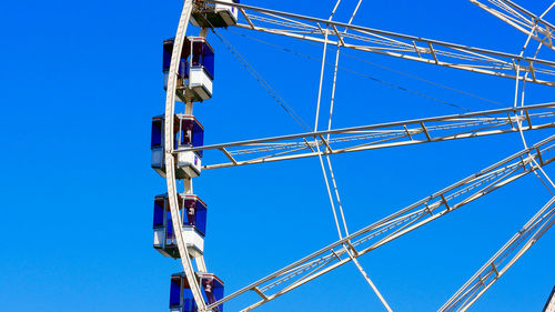 Low angle view of ferris wheel against clear blue sky