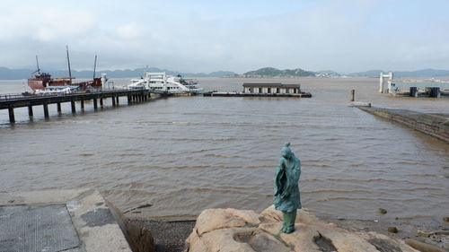 Rear view of men on pier over sea against sky