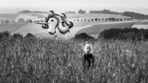 Rear view of girl holding balloon standing on field