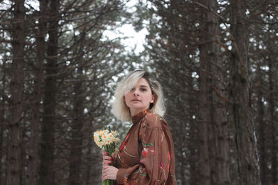 Portrait of woman standing in snow covered forest