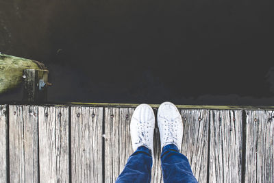 Low section of man standing over lake on pier