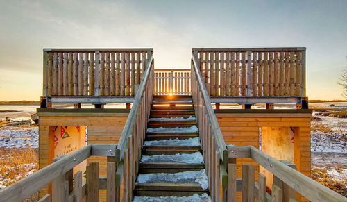 View of staircase by sea against sky during sunset