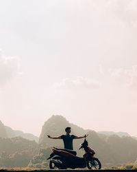 Man riding bicycle on mountain against sky