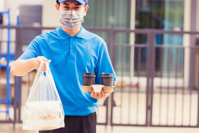 Portrait of young man holding blue while standing outdoors