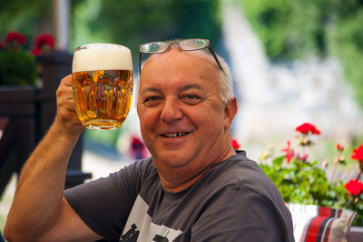 Portrait of smiling man holding beer glass outdoors