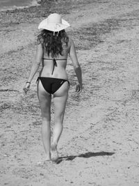 Rear view of woman in bikini walking on beach