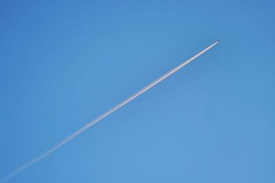 Low angle view of vapor trail against clear blue sky