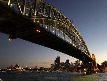 Illuminated bridge over river in city at night