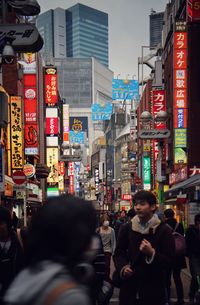 People walking on street amidst buildings in city