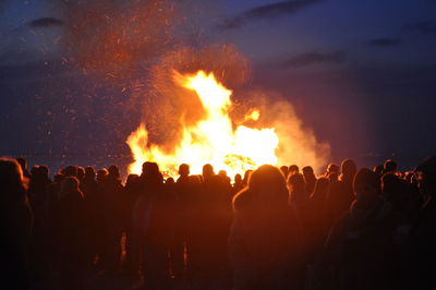 Crowd standing by bonfire at night