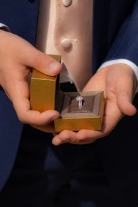 Full frame close-up view of the groom holding the wedding ring box open