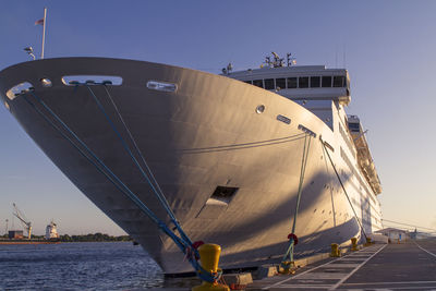 A grand cruise ship moored at the harbor, bathed in sunrise.