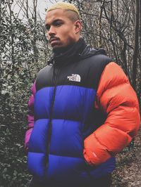 Portrait of young man standing against trees