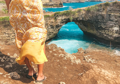 Low section of woman standing on rock by sea