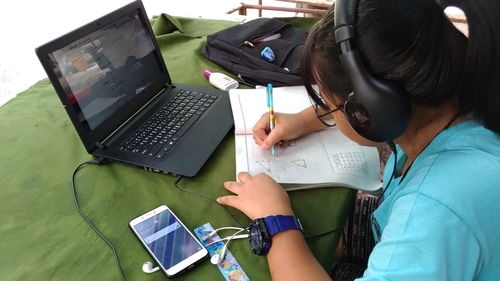 Girl drawing diagram while watching video in laptop