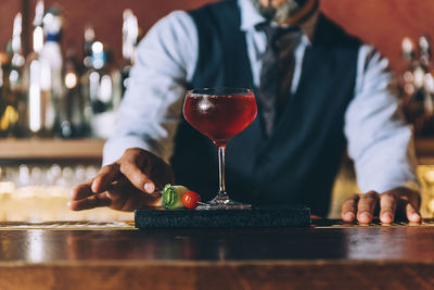 Midsection of mature bartender preparing cocktail in bar