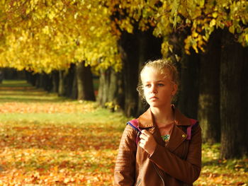 Girl standing while looking away against trees at park