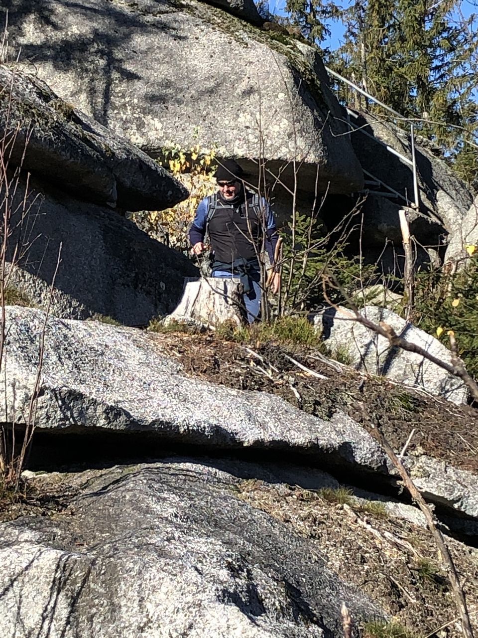 MAN SITTING ON ROCK AGAINST SKY