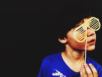 Boy holding novelty glasses over black background