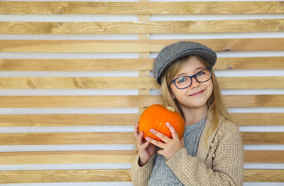 Portrait of smiling young woman wearing hat against wall