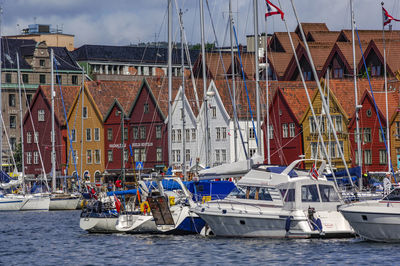 Sailboats moored in sea against buildings in city