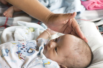 The baby girl was lying on a white cloth, with her mother's hand touching the forehead.