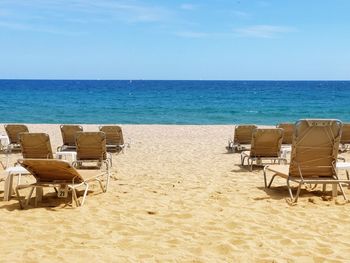 Chairs on beach against sky