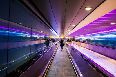 People walking on illuminated moving walkway