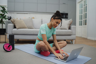 Young woman using laptop while sitting on sofa at home