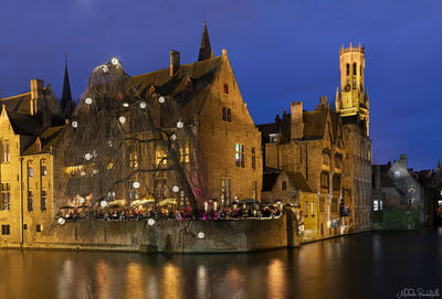 Panoramic view of illuminated buildings by river against sky in city