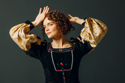 Side view of young woman standing against black background