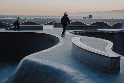 People skateboarding at beach against sky