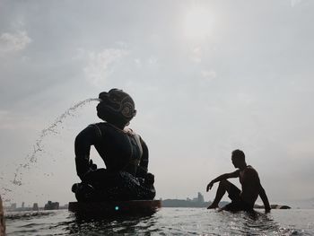 Man sitting by sculpture in infinity pool