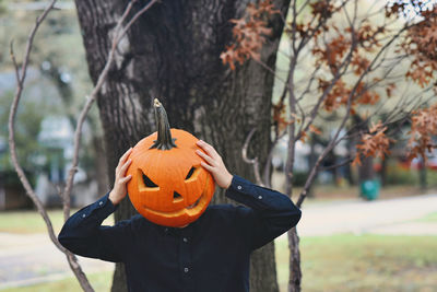Person having fun with a carved pumpkin head