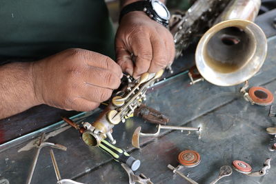 Midsection of man repairing musical instrument in workshop