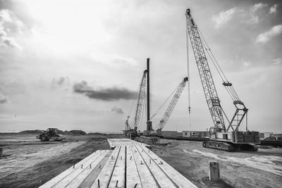 Cranes at construction site against sky
