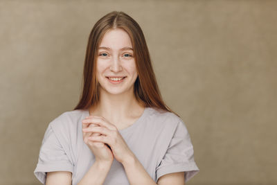 Portrait of young woman standing against wall