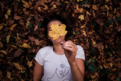 Low section of boy holding leaves during autumn