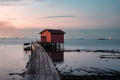 Sunrise view of wooden bridge and red house background at clan tan jetty, penang, malaysia.