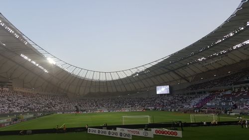 People playing soccer on field against sky