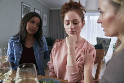 Friends consoling depressed woman at home