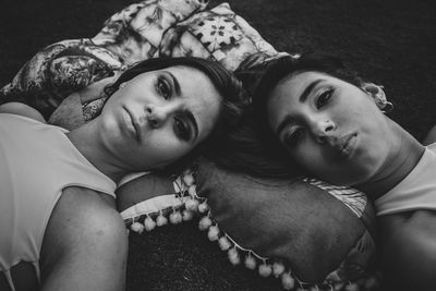 Portrait of friends lying with pillows on field