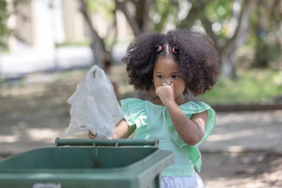 Girl throwing garbage in can outdoors